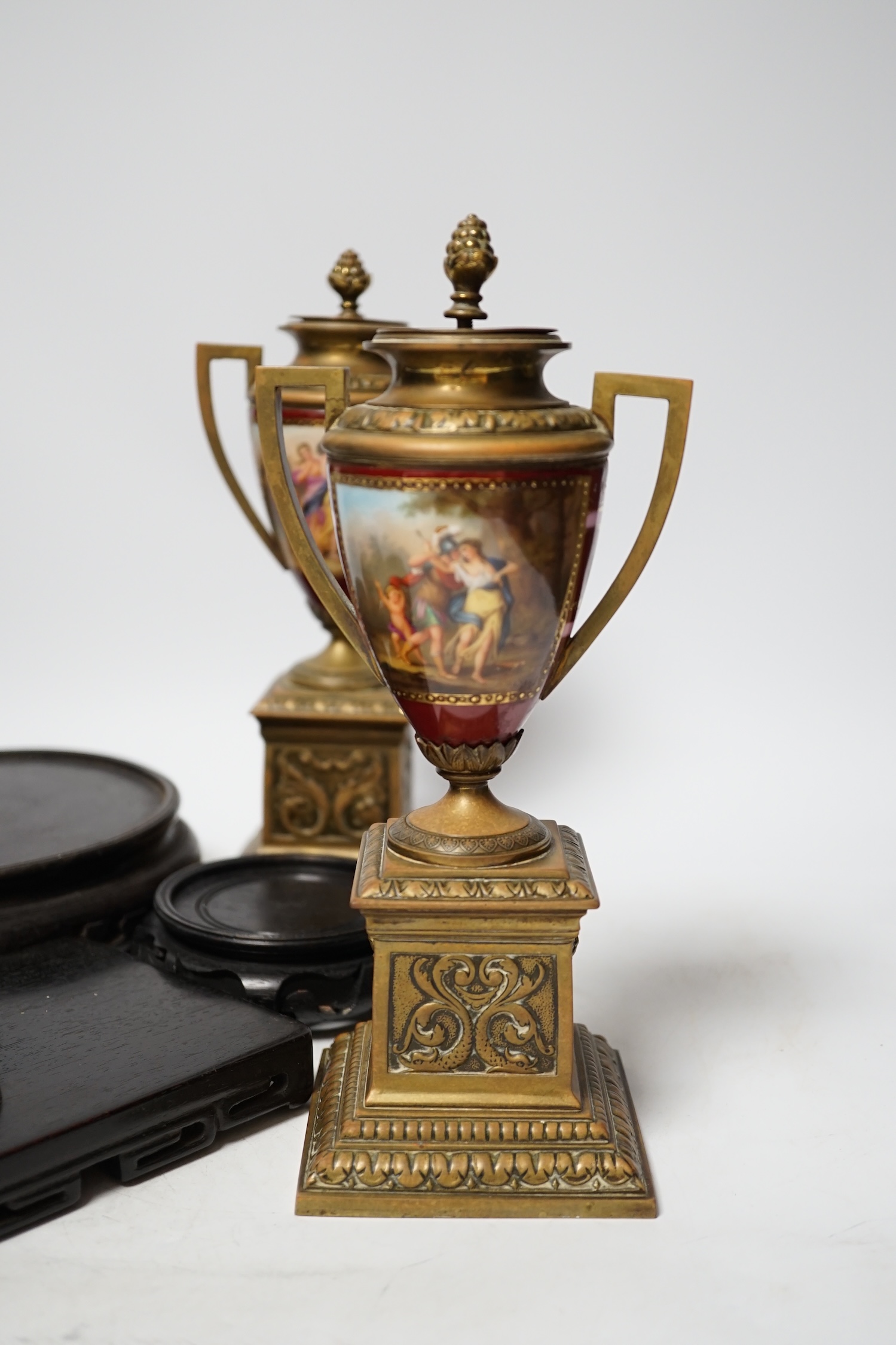 A pair of Vienna style brass mounted urns with enamelled classical scenes and six various Chinese carved hardwood stands, 23cm high